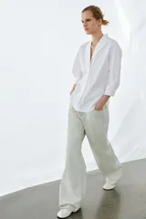 Camisa de algodón con cuello redondo y escote en pico, de manga tres cuartos con puños y bajo asimétrico redondeado.