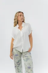 Camisa blanca amplia de manga corta, con cuello clásico y botones al frente.