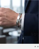 Pulsera rígida de acero inoxidable con diseño de guarda griega en los extremos y placa central lisa apta para grabado.