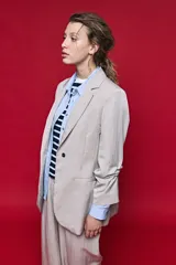 Blazer beige de corte recto, con solapa clásica, bolsillos frontales con solapa y cierre de un botón.