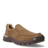 Zapatos tipo slip-on Caterpillar, confeccionados en lona color beige, con suela de goma robusta en tono marrón y detalle de marca en el lateral.