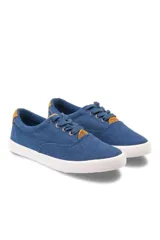 Championes de lona azul con cordones tono sobre tono, suela blanca de goma y detalles en color tostado en el talón y en la lengüeta.