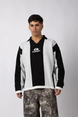 Sweater de tejido de punto con diseño de rayas verticales en tonos beige y blanco. Presenta cuello polo abierto, mangas largas y un corte holgado. Incluye un logo bordado en el centro del pecho.