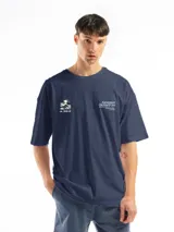 Remera de corte oversized color azul marino, con estampa gráfica minimalista en el pecho que incluye una ilustración de una ola y texto tipográfico.