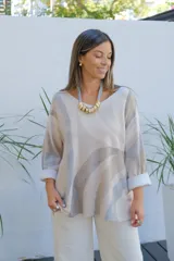 Sweater de punto con diseño de ondas en tonos beige y gris, de corte amplio, escote en V y mangas largas con puños vueltos.