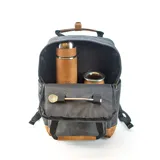 Mochila matera y porta notebook en tela canvas de color marrón, con diseño funcional que incluye bolsillo frontal con cierre, correas ajustables, manija superior y detalles de tiras de lona con hebillas metálicas.