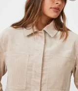 Campera corta color beige de pana con cuello camisero, cierre frontal con botones, bolsillos de parche en el pecho y mangas largas con puños abotonados.