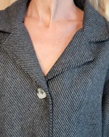 Sobrecamisa de paño color beige, con cuello solapa, cierre frontal de botones y dos bolsillos delanteros con solapa.