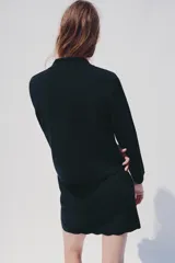 Chaqueta de punto color azul marino, con cuello solapa, manga larga y cierre frontal con botones metálicos. Presenta terminaciones en ondas en el bajo y los puños.