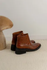 Bota corta de cuero marrón con panel trasero de gamuza en tono más oscuro, suela de goma negra y taco cuadrado bajo.