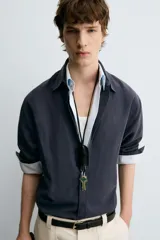 Camisa de manga larga color azul marino oscuro, con cuello italiano y corte relajado (relaxed fit). Presenta cierre frontal de botonadura.