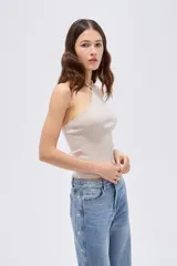 Top de viscosa color marrón, con diseño al cuerpo, escote halter y detalle de cuentas en el cuello.