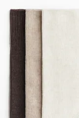 Pack de tres pares de medias largas de punto acanalado, en tonos marrón oscuro, beige y blanco.