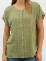 Blusa de corte fluido confeccionada en algodón con tejido texturizado de patrón a cuadros. Presenta mangas cortas caídas, escote redondo y cierre frontal con botones.