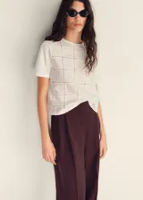 Camiseta blanca de algodón con diseño calado geométrico, corte recto y mangas cortas.