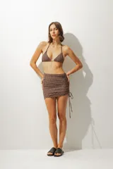 Falda corta tipo pareo con diseño de rayas verticales en tonos azul y negro. Presenta un lateral fruncido con cordón ajustable que permite regular el largo y el ajuste de la prenda.