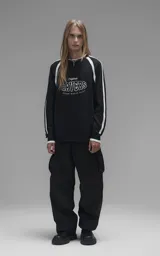 Sweater de punto negro con cuello redondo, mangas largas con franjas laterales blancas y puños en punto rib. Presenta un diseño gráfico bordado en el pecho con la inscripción 'RAVERS' y detalles en blanco.