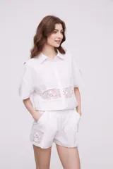 Camisa blanca de algodón con apliques de crochet calado en la cintura, manga corta y cuello camisa.