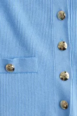 Cárdigan corto de punto acanalado en color celeste, con cuello redondo, manga corta y cierre frontal de botones dorados. Presenta dos bolsillos delanteros decorativos con botón dorado.