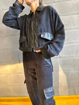 Conjunto negro de pana compuesto por una chaqueta con cuello de cuero sintético, cierre frontal con cremallera y bolsillos con solapa, y un pantalón de corte recto con bolsillos laterales.