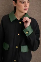 Campera corta en tono beige con cuello, puños, solapas de bolsillos frontales y detalles en cuero sintético marrón. Cuenta con cierre frontal de botones dorados y bolsillos aplicados.