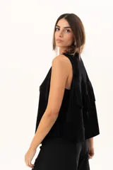 Chaleco oversize de cuero descarne color negro, con diseño de terminación en picos, flecos en la espalda y detalle de tachas metálicas a lo largo de los bordes frontales.