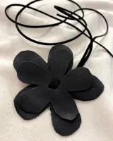 Gargantilla con dije de flor de cuero negro y tira de cuero negro para atar.