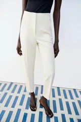 Pantalón de tiro alto y corte slim fit, de largo tobillero, color beige claro con costuras marcadas en la parte delantera.