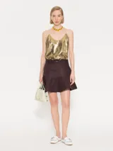 Top corto dorado con breteles finos y espalda cruzada con flecos.