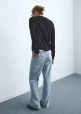 Pantalón de jean estilo wide leg con tiro alto, cinco bolsillos, trabillas para cinturón y bajo deshilachado.