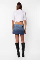 Minifalda de jean azul con lavado degradé, tiro medio con doble cintura, bolsillos delanteros y traseros, cierre metálico y dos botones personalizados.
