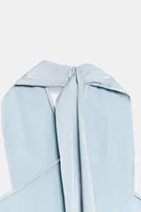 Top de cuello halter con diseño cruzado en el frente, confeccionado en tejido satinado. Presenta bajo asimétrico con detalle de lazada y cierre posterior con botones.