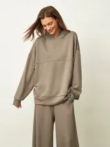Buzo oversize color gris topo, con capucha y bolsillo canguro.