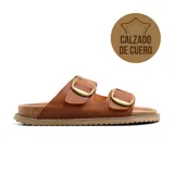 Sandalias bajas de cuero color beige con doble tira y hebillas metálicas doradas.