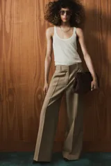 Pantalón de tiro medio confeccionado en tejido con lana, de corte recto y pernera ancha. Presenta detalle de nervio delantero, trabillas en la cintura, bolsillos laterales y cierre frontal con cremallera, botón y ganchos metálicos.