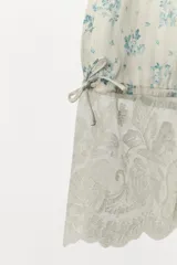 Pantalón bombacho de tiro medio y cintura elástica, confeccionado en viscosa con estampado floral y rayas sutiles. Presenta bajo ajustable con lazada y aplicación de encaje contrastante en el ruedo.