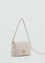 Bolso de hombro pequeño en color beige, con diseño minimalista de solapa y cierre frontal con botón joya metálico. Cuenta con un asa larga ajustable mediante un nudo lateral.