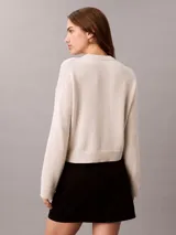Sweater Calvin Klein de punto color blanco, de corte regular y manga larga, con cuello redondo y el logo de la marca en relieve en el pecho. Cuenta con puños y dobladillo acanalados.