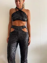Pantalón de lentejuelas negro con aberturas en la cadera y corte recto.