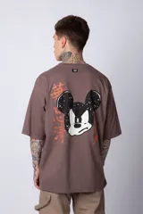 Remera negra de algodón de corte oversize, con mangas cortas y cuello redondo. Estampado pequeño en el frente y diseño grande en la espalda con Mickey Mouse y caracteres orientales en tonos rojizos.