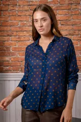 Camisa de manga larga con estampado de leopardo, cuello clásico y cierre frontal de botones. Presenta un corte holgado y puños abotonados.