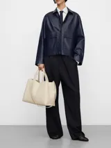 Bolso shopper horizontal de poliuretano color beige, con dos compartimentos, cierre magnético, bolsillo interior con cierre, asa de mano y asa larga regulable y extraíble. Incluye logo grabado en el frente.