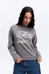 Remera de manga larga color beige, con cuello redondo y estampa gráfica frontal en color celeste.