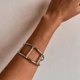 Brazalete rígido plateado con diseño geométrico de tres rectángulos unidos.