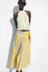 Falda midi tipo pareo de tiro medio, confeccionada en algodón con diseño de rayas verticales en tonos amarillo, gris y blanco. Presenta un bajo asimétrico y cierre lateral con lazada.