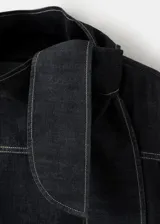 Blusa de mezclilla negra con costuras en contraste, cuello alto y solapa trasera.