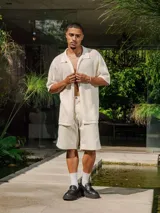 Camisa de manga corta confeccionada en tejido de punto abierto color crudo, con cuello tipo polo y diseño de calce holgado.