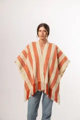 Ruana tejida a mano en Uruguay, con lana merino color crudo y franjas verticales color terracota.