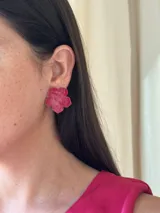 Aros tipo botón con forma de flor color fucsia con brillo.