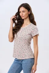 Remera blanca de manga corta con estampado floreado, cuello redondo y detalle de botones frontales.